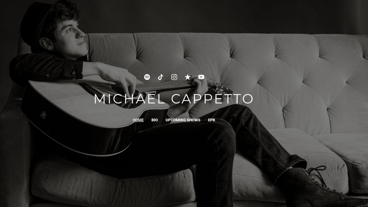 michael cappetto leaning back on couch playing guitar